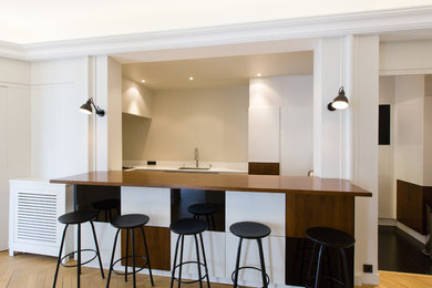 Cette photo montre une salle à manger ouverte sur la cuisine tendance de taille moyenne avec un mur blanc, parquet clair et aucune cheminée.