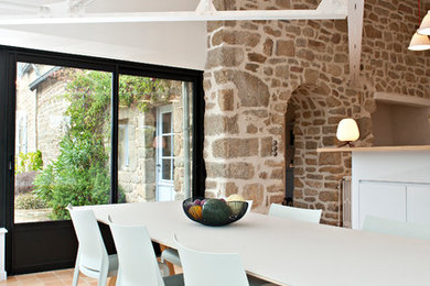 Cette photo montre une grande salle à manger ouverte sur le salon nature avec un mur beige et tomettes au sol.