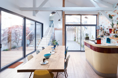 Cette image montre une salle à manger ouverte sur le salon bohème de taille moyenne avec parquet clair, un sol beige et un mur multicolore.