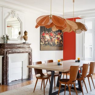 Réalisation d'une grand salle à manger design fermée avec un mur blanc, un sol en bois brun, une cheminée standard, un manteau de cheminée en pierre et un sol marron.