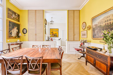 Cette photo montre une salle à manger ouverte sur le salon tendance de taille moyenne avec un mur jaune, parquet clair et aucune cheminée.