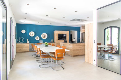 Idée de décoration pour une salle à manger ouverte sur la cuisine design avec un mur bleu, un sol en carrelage de céramique et un sol beige.