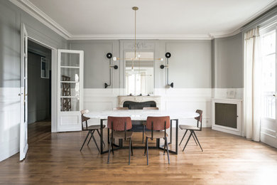Exemple d'une grande salle à manger ouverte sur le salon tendance avec un mur gris, parquet foncé, une cheminée standard, un manteau de cheminée en pierre et un sol marron.