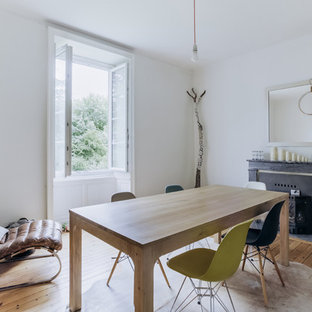 Idées déco pour une salle à manger scandinave fermée avec un mur blanc, un sol en bois clair, une cheminée standard et un manteau de cheminée en bois.
