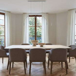 Cette photo montre une salle à manger tendance avec un sol en bois clair, un mur beige et un sol beige.
