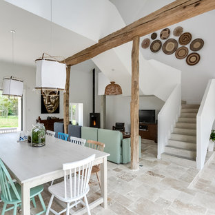 Cette photo montre une grand salle à manger scandinave avec un mur blanc, un poêle à bois, un sol beige et béton au sol.