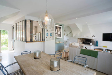 Réalisation d'une salle à manger ouverte sur le salon design de taille moyenne avec un mur blanc, tomettes au sol, un sol beige, une cheminée standard et un manteau de cheminée en pierre.
