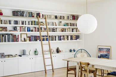 Cette image montre une grande salle à manger design avec un mur blanc et un sol marron.