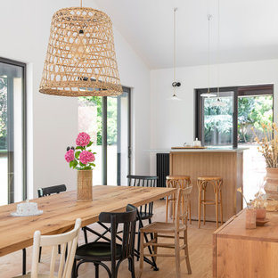 Réalisation d'une grand salle à manger ouverte sur le salon champêtre avec un sol en bois clair.