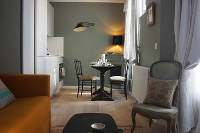 Cette image montre une petite salle à manger ouverte sur le salon traditionnelle avec un mur vert, parquet clair, un poêle à bois et un sol marron.