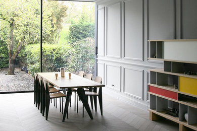 Imagen de comedor contemporáneo grande sin chimenea con paredes grises y suelo de madera clara