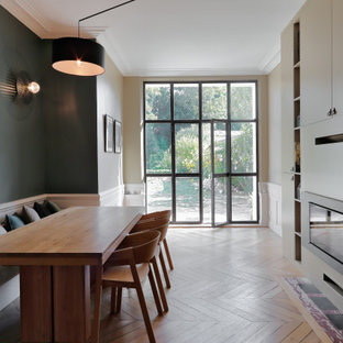 Idées déco pour une salle à manger contemporaine de taille moyenne avec un mur beige, un sol en bois brun, aucune cheminée, un manteau de cheminée en métal et un sol beige.