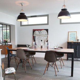 Foto di una grande sala da pranzo aperta verso il soggiorno industriale con parquet chiaro, pavimento marrone, pareti bianche, camino classico e cornice del camino in legno