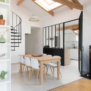 Aménagement d'une salle à manger avec un mur blanc, un poêle à bois, un manteau de cheminée en métal et un sol gris.