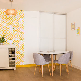 Cette photo montre une grand salle à manger ouverte sur le salon rétro avec un mur jaune, un sol en bois clair et aucune cheminée.