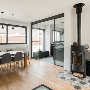 Idée de décoration pour une grand salle à manger design avec un sol en bois clair et un poêle à bois.