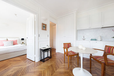 Cette image montre une salle à manger ouverte sur la cuisine traditionnelle de taille moyenne avec un mur blanc, un sol en bois brun et éclairage.