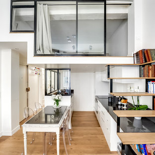 Cette photo montre une salle à manger ouverte sur le salon tendance de taille moyenne avec un mur blanc, un sol en bois brun et aucune cheminée.
