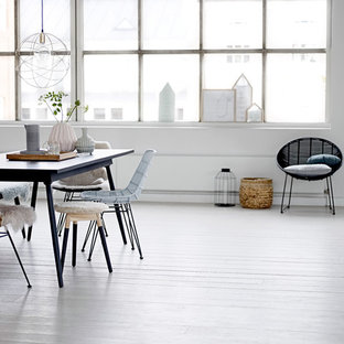 Réalisation d'une grand salle à manger ouverte sur le salon bohème avec un mur blanc et un sol en bois peint.