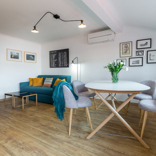 Cette photo montre une salle à manger ouverte sur le salon tendance de taille moyenne avec un mur blanc, un sol en bois brun et aucune cheminée.