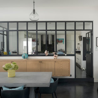 Idées déco pour une salle à manger contemporaine avec un mur blanc et un sol noir.