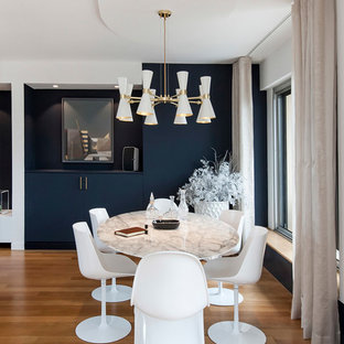Aménagement d'une grand salle à manger ouverte sur le salon contemporaine avec un mur bleu, un sol en bois clair, cheminée suspendue, un manteau de cheminée en plâtre et un sol beige.