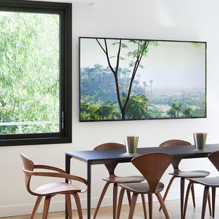 Cette photo montre une salle à manger ouverte sur le salon tendance avec un mur blanc, un sol en bois clair et un sol beige.