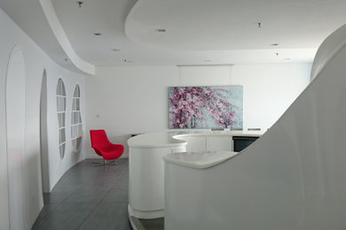 Réalisation d'une salle à manger ouverte sur la cuisine design avec un mur blanc, un sol en carrelage de porcelaine et un sol gris.