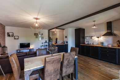 Cette image montre une salle à manger ouverte sur le salon urbaine de taille moyenne avec un mur blanc, un sol en bois brun et aucune cheminée.