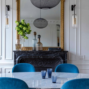 Exemple d'une salle à manger ouverte sur le salon chic de taille moyenne avec un mur blanc, un sol en bois clair, une cheminée standard, un manteau de cheminée en pierre et un sol beige.