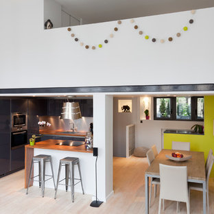 Exemple d'une grand salle à manger ouverte sur le salon tendance avec un mur jaune, un sol en bois clair et aucune cheminée.
