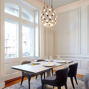 Idée de décoration pour une grand salle à manger ouverte sur le salon design avec un mur blanc, un sol en bois brun, un sol marron et boiseries.