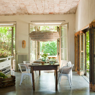 Modelo de comedor de cocina de estilo de casa de campo, grande, con paredes beige y suelo de cemento