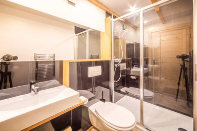 Idee per una stanza da bagno con doccia stile rurale di medie dimensioni con doccia alcova, WC sospeso, piastrelle nere, piastrelle a specchio, pareti nere, pavimento con piastrelle in ceramica, lavabo sospeso, top in laminato e pavimento beige
