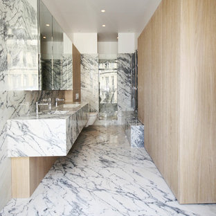 Exemple d'une grand salle de bain tendance avec un WC suspendu, des dalles de pierre, un lavabo intégré, un plan de toilette en marbre, un carrelage gris et un carrelage blanc.