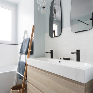 Inspiration pour une salle de bain principale nordique de taille moyenne avec une baignoire posée, un carrelage blanc, un placard à porte plane, des portes de placard en bois clair, un carrelage métro, un sol noir, un combiné douche/baignoire, un WC séparé, un mur blanc, un sol en carrelage de céramique, une grande vasque, un plan de toilette en surface solide et un plan de toilette blanc.