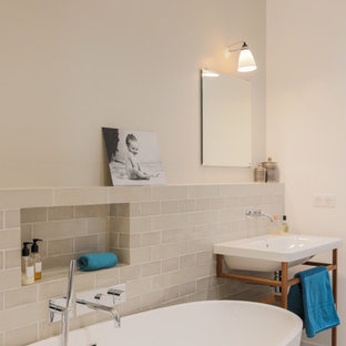 Inspiration pour une salle d'eau design de taille moyenne avec un combiné douche/baignoire, un mur beige, un sol beige, aucune cabine, une baignoire indépendante, un carrelage beige et un lavabo suspendu.