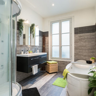 Idée de décoration pour une salle de bain principale design avec un placard à porte plane, des portes de placard noires, une baignoire indépendante, une douche d'angle, un carrelage beige, un carrelage gris, un mur multicolore, un plan vasque, un sol multicolore, une cabine de douche à porte coulissante et un plan de toilette blanc.