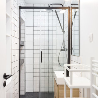 Cette photo montre une salle de bain scandinave avec un placard à porte plane, des portes de placard en bois clair, un carrelage blanc, des carreaux de céramique, un mur blanc, un lavabo suspendu, un sol gris et une cabine de douche à porte coulissante.