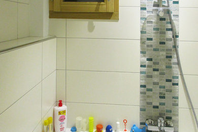 Cette image montre une salle de bain minimaliste de taille moyenne pour enfant avec une baignoire encastrée, un carrelage blanc, parquet clair, aucune cabine, un espace douche bain, mosaïque et un mur beige.