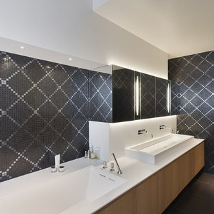 Idées déco pour une grand douche en alcôve principale contemporaine avec des portes de placard en bois clair, une baignoire encastrée, un carrelage gris, carrelage en mosaïque, un mur blanc, un sol en carrelage de céramique, une grande vasque, un plan de toilette en surface solide et un placard à porte plane.