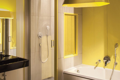 Cette photo montre une salle de bain principale tendance de taille moyenne avec WC suspendus, une baignoire posée, un mur jaune et un lavabo suspendu.