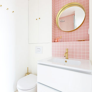 Aménagement d'une petit salle de bain principale scandinave avec un placard à porte affleurante, des portes de placard blanches, une douche d'angle, un WC suspendu, un carrelage rose, carrelage en mosaïque, un mur blanc, un sol en terrazzo, un lavabo de ferme, un plan de toilette en carrelage, un sol multicolore, une cabine de douche à porte battante et un plan de toilette rose.