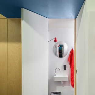 Aménagement d'une petit salle de bain contemporaine avec un lavabo suspendu, un carrelage blanc, un mur blanc et un sol noir.