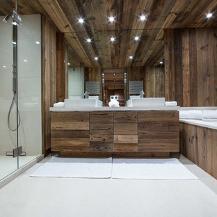 Cette photo montre une grand salle de bain montagne avec des portes de placard en bois sombre, une baignoire encastrée, un mur marron et un lavabo posé.