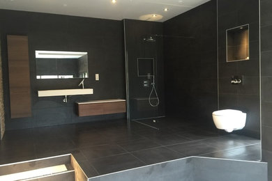 Inspiration pour une très grande salle de bain principale design en bois brun avec une douche à l'italienne, WC suspendus, un carrelage noir, un carrelage de pierre, un mur noir, un sol en ardoise et une vasque.