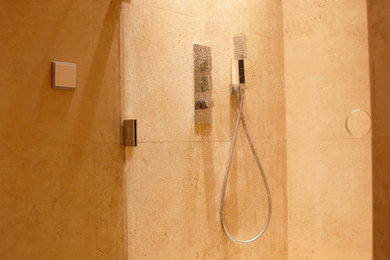 Inspiration pour une petite salle d'eau minimaliste avec un placard à porte affleurante, des portes de placard grises, une douche à l'italienne, WC suspendus, un carrelage beige, des dalles de pierre, un mur beige et un lavabo encastré.
