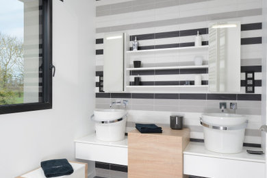 Aménagement d'une salle de bain contemporaine de taille moyenne avec un carrelage gris, meuble double vasque, un lavabo posé, une cabine de douche à porte battante, un plan de toilette blanc, meuble-lavabo suspendu, une douche à l'italienne, un sol en carrelage de céramique et un sol gris.