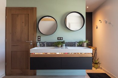 Photo of a large contemporary ensuite bathroom in Strasbourg with flat-panel cabinets, black cabinets, a built-in bath, a built-in shower, a two-piece toilet, black tiles, ceramic tiles, green walls, ceramic flooring, a console sink, solid surface worktops, grey floors, an open shower and white worktops.