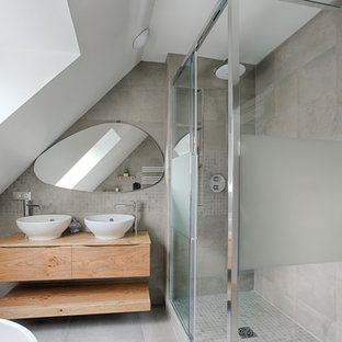 Idée de décoration pour une grand salle de bain minimaliste avec un placard à porte plane, des portes de placard en bois clair, une douche à l'italienne, un carrelage gris, un mur gris, un lavabo posé, un plan de toilette en bois, un sol gris, une cabine de douche à porte coulissante et un plan de toilette marron.